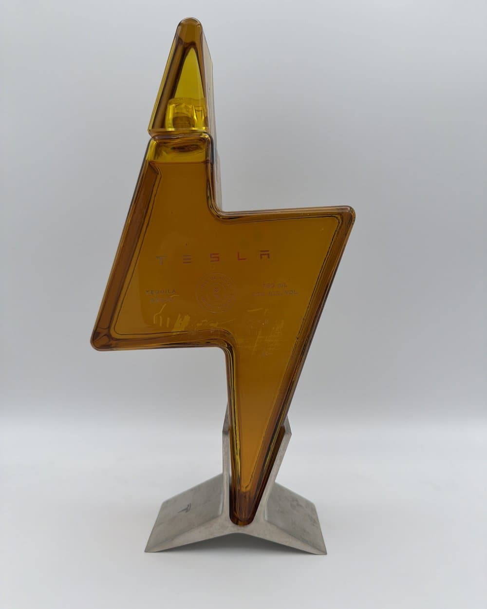 Tesla Tequila añejo lightning-bolt decanter on its stand, purchased by We Buy Bottles